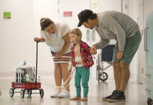 Harry being helped to walk by his parents in hospital after heart surgery
