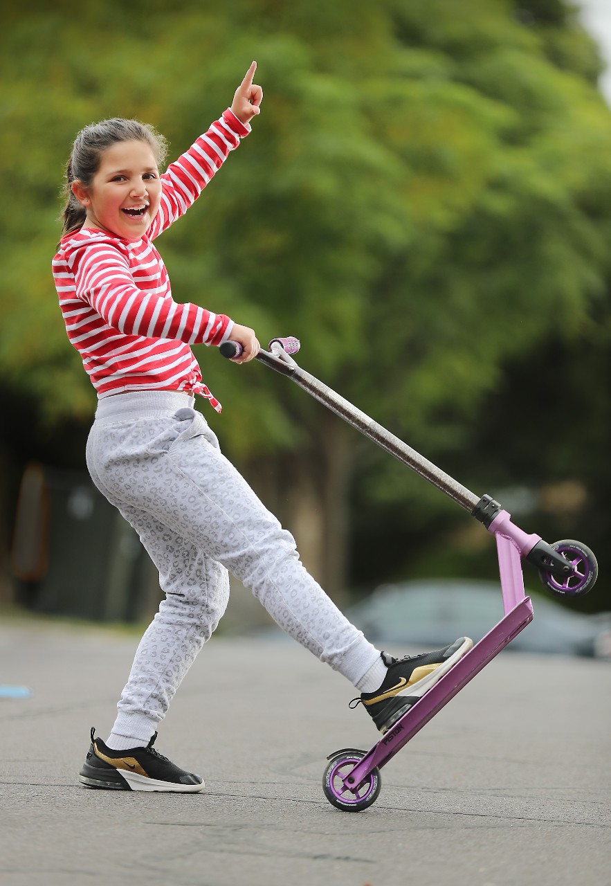 Ariana on her scooter, holding an arm up in the air