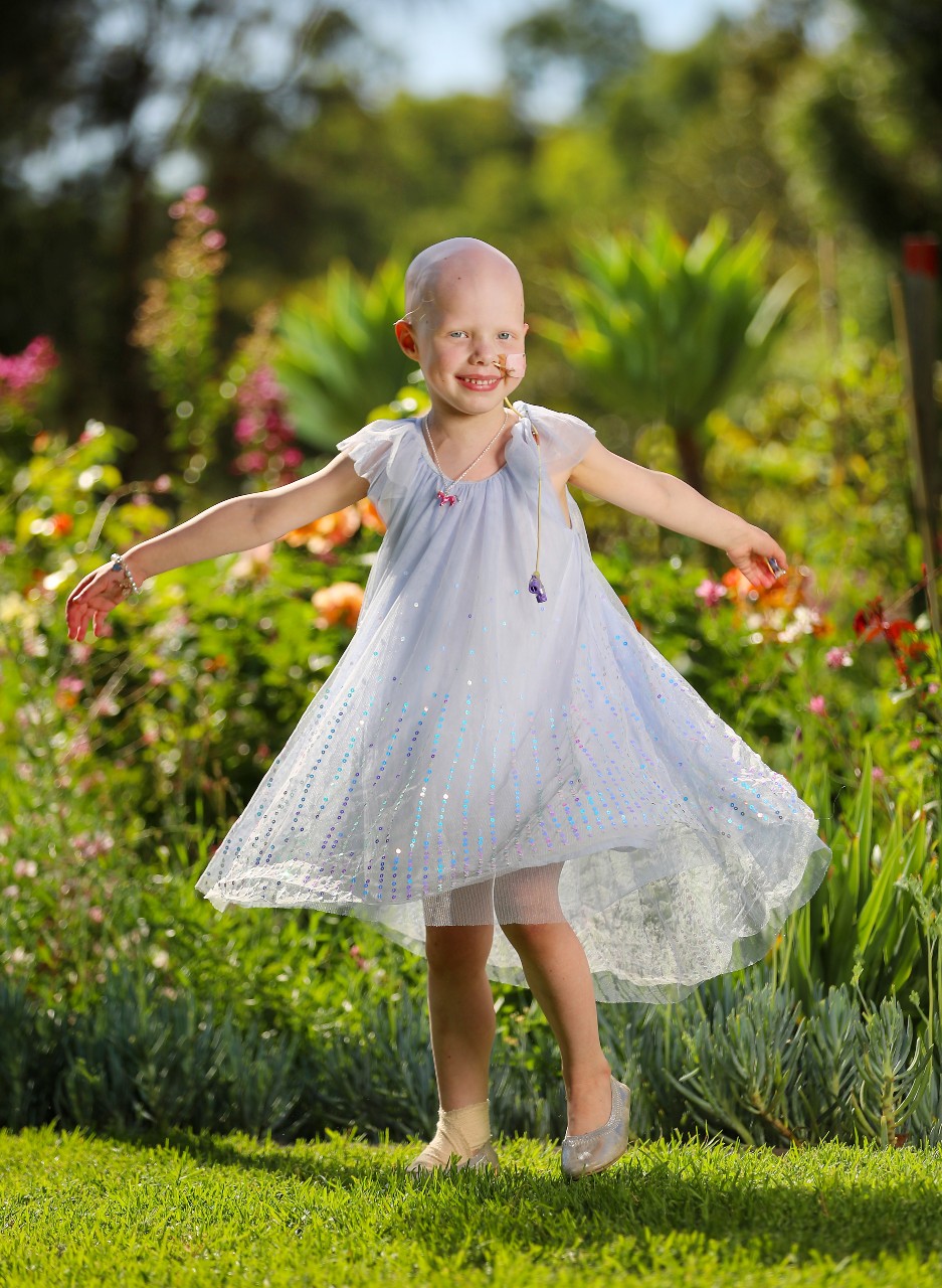 Lucy standing in the garden holding her arms out to her sides