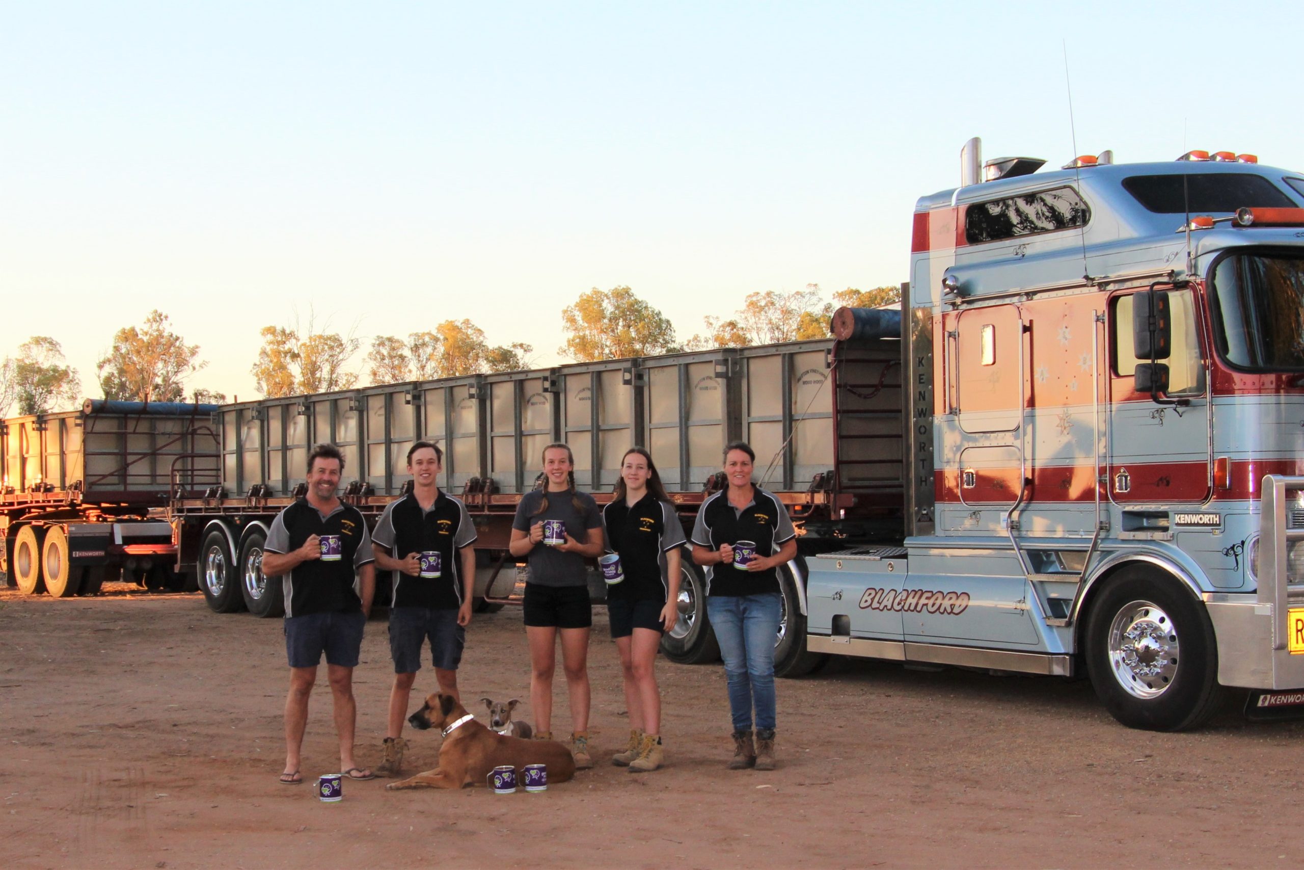 Annette Blachford and her family standing in front of a road train truck, all holding collection tins