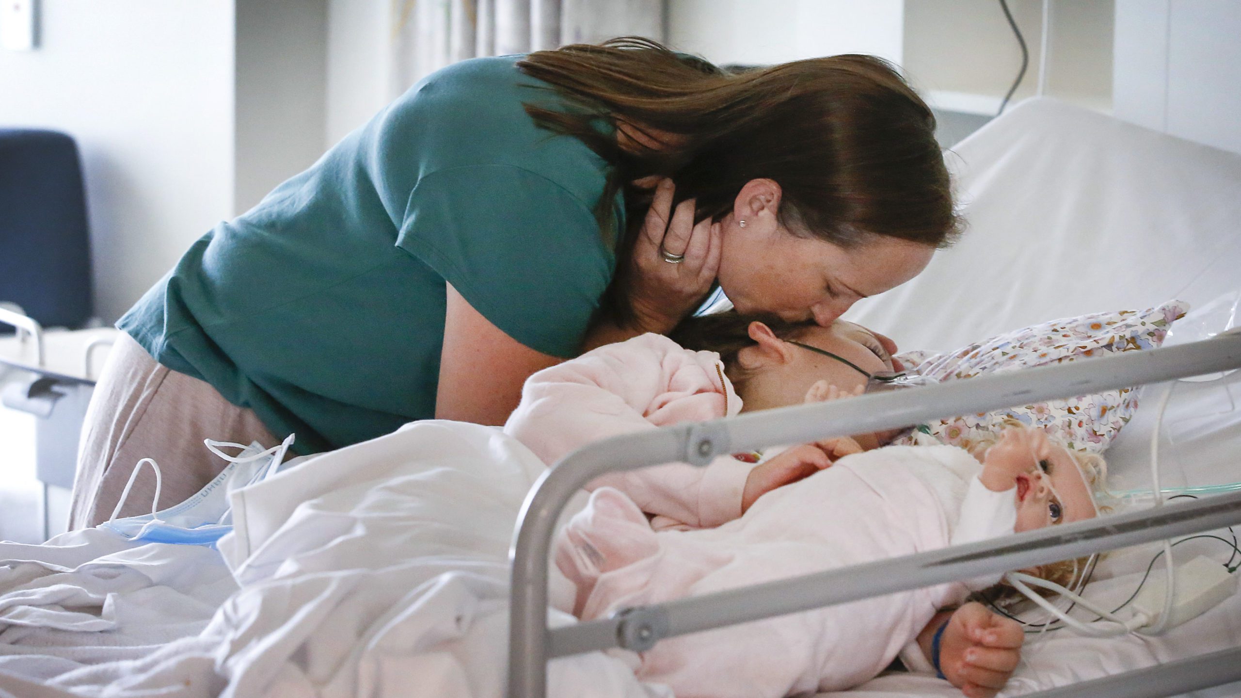 Mum Sara kisses her daughter Piper who is lying in her hospital bed