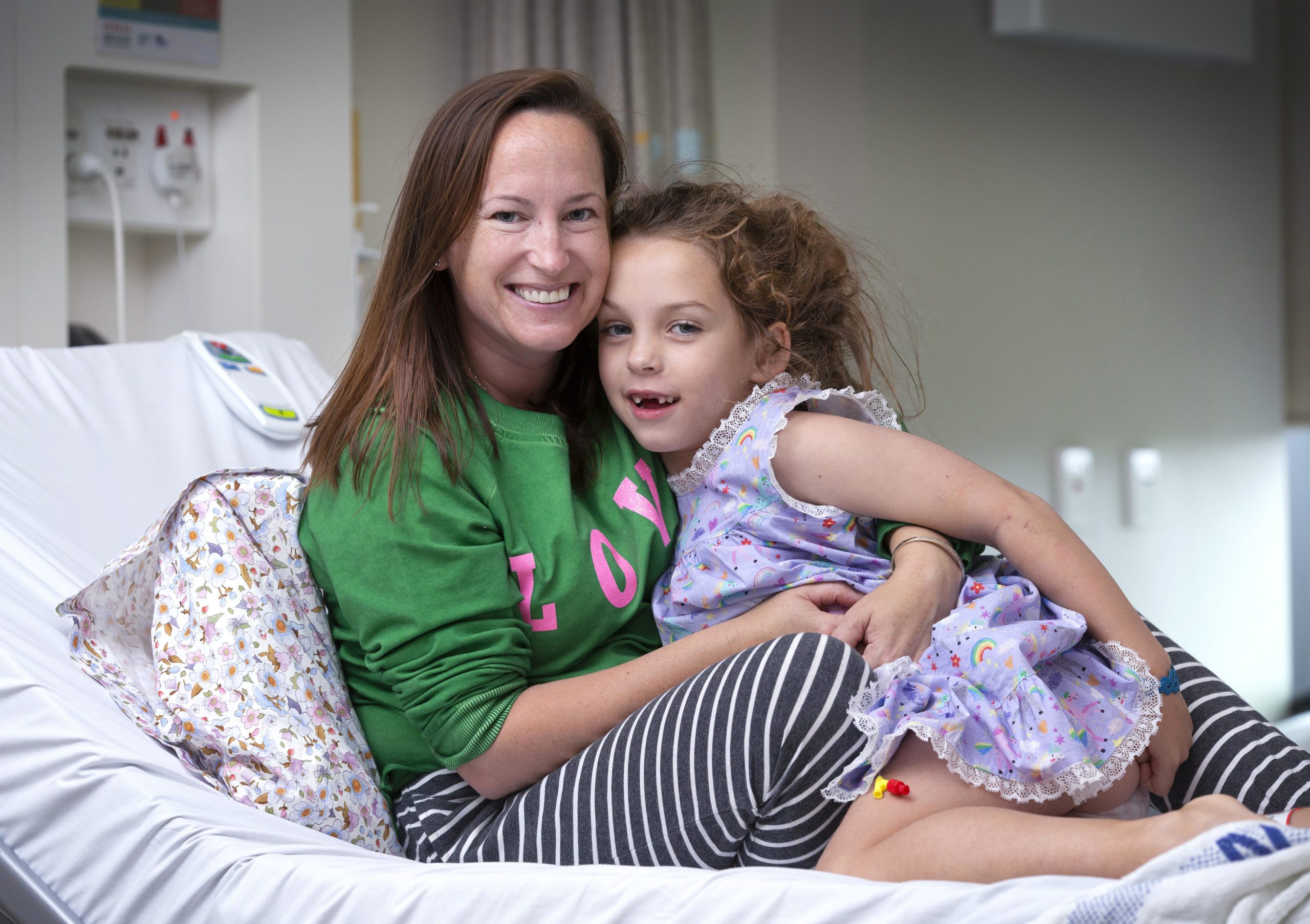 Piper sitting with her mum Sara on her hospital bed