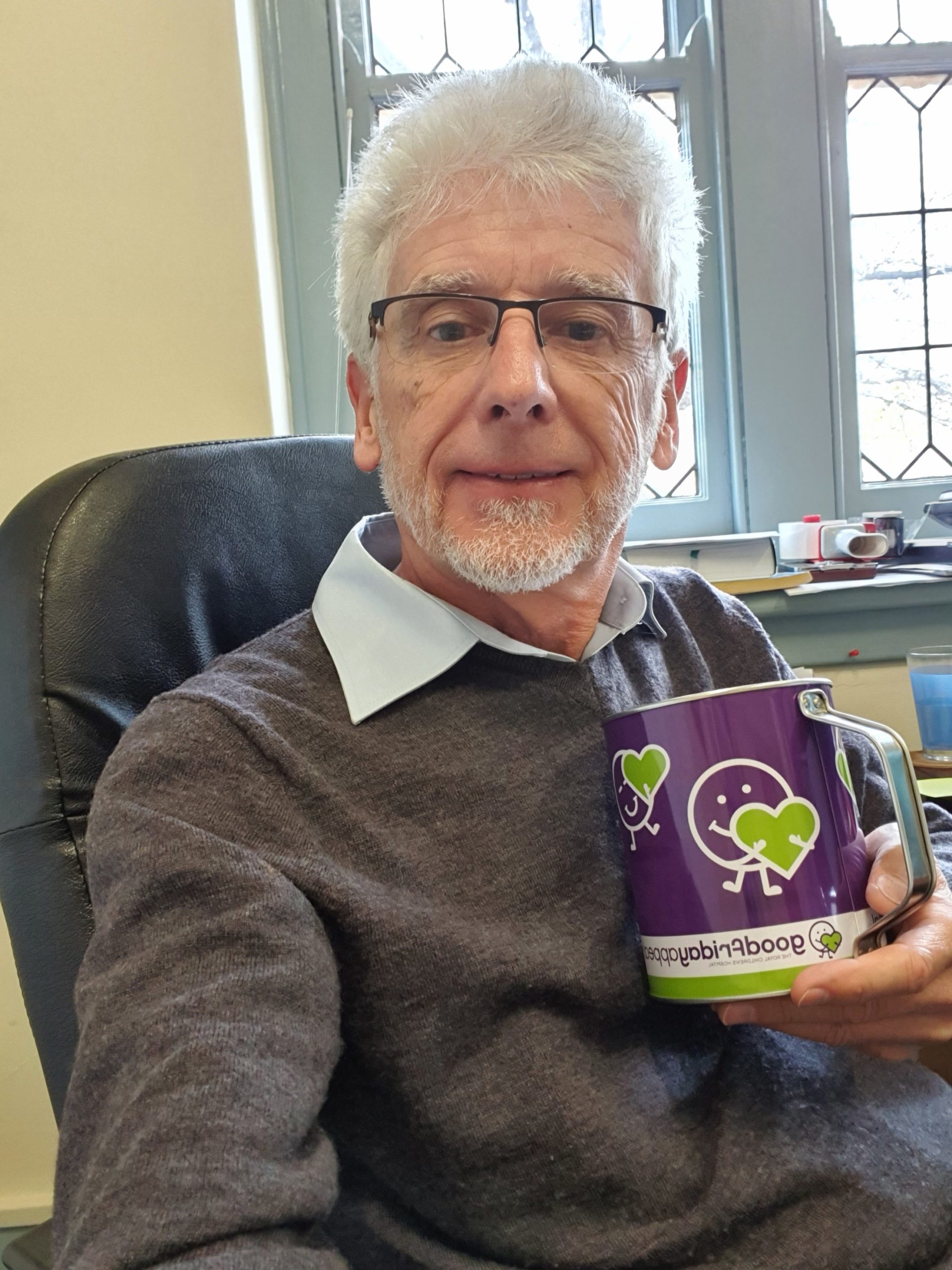 Phil sitting on a chair and holding a GFA purple collection tin