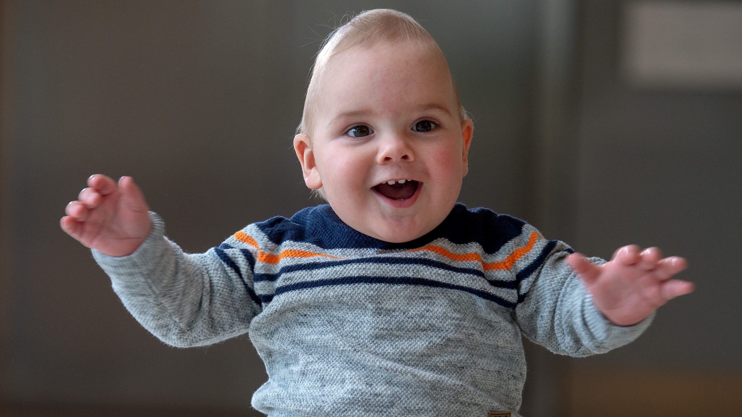 William sitting and smiling with his arms held out wide in front of him