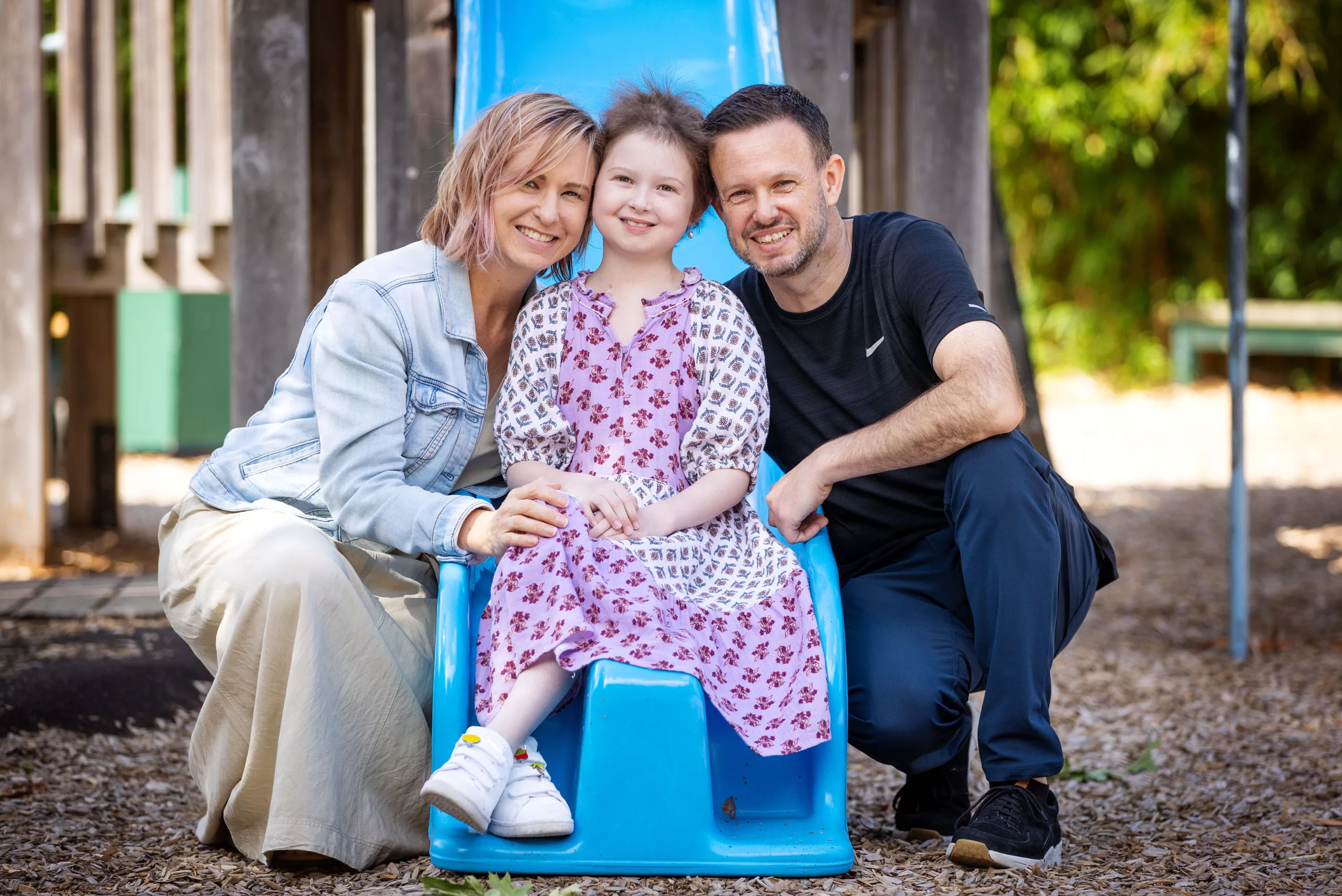 Imogen with her parents either side of her on a blue slide