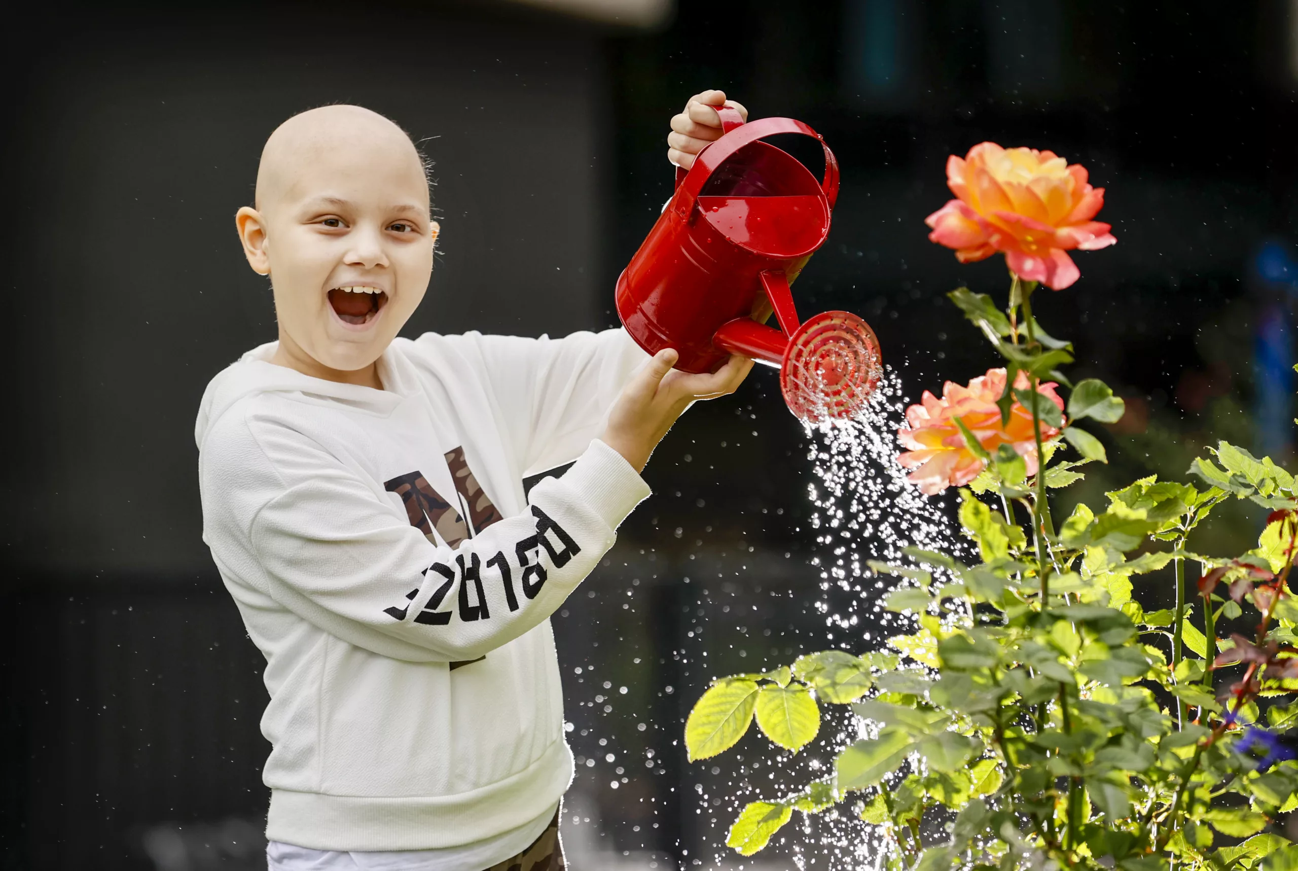 Patient with a red watering can, watering, gardening in the newly funded GARDEN PROGRAM VISION.